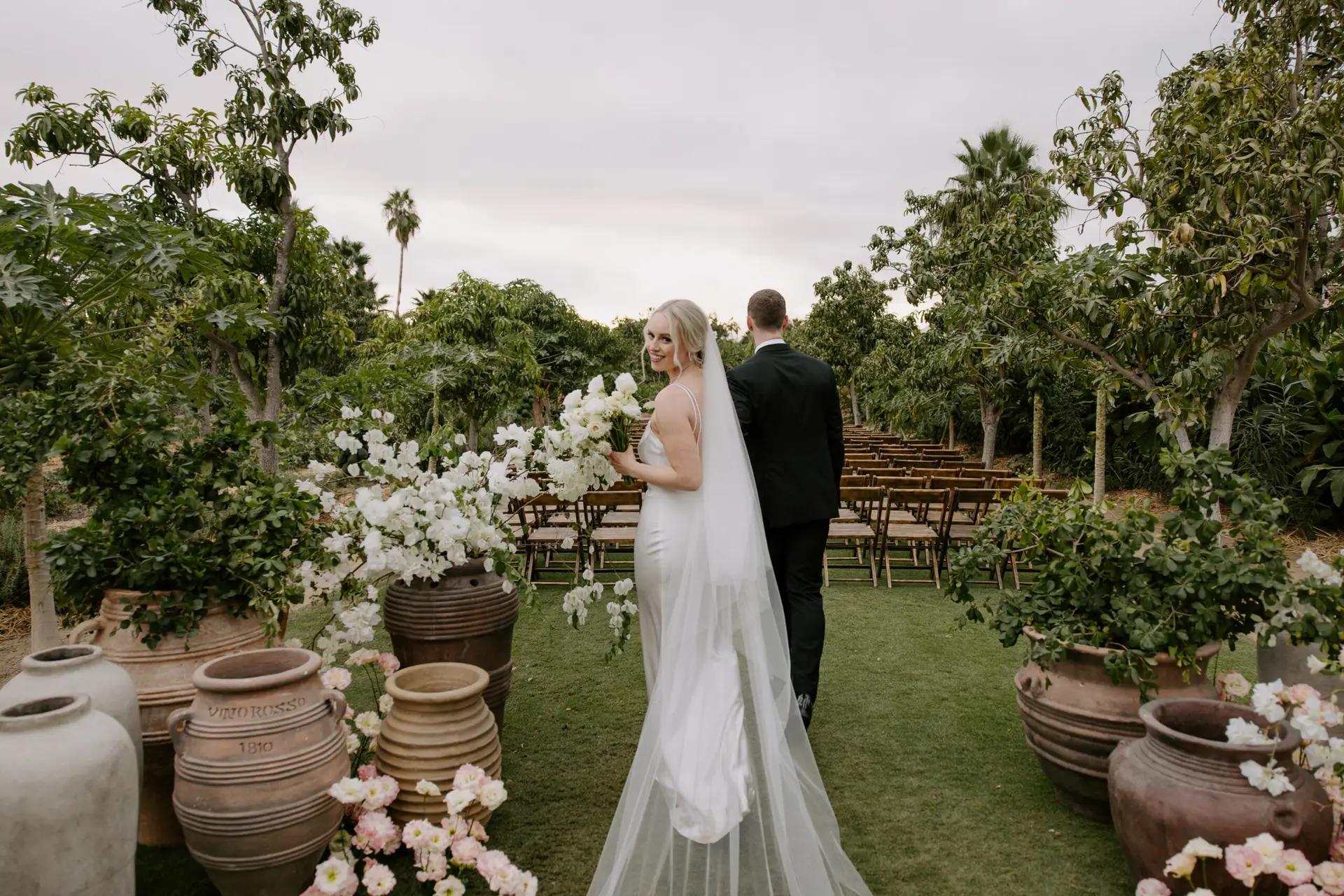 Bride and groom walking through garden Photo taken by Ximena Zermeño Global Luxury Destination Wedding Photographer, ximenazermeno.com